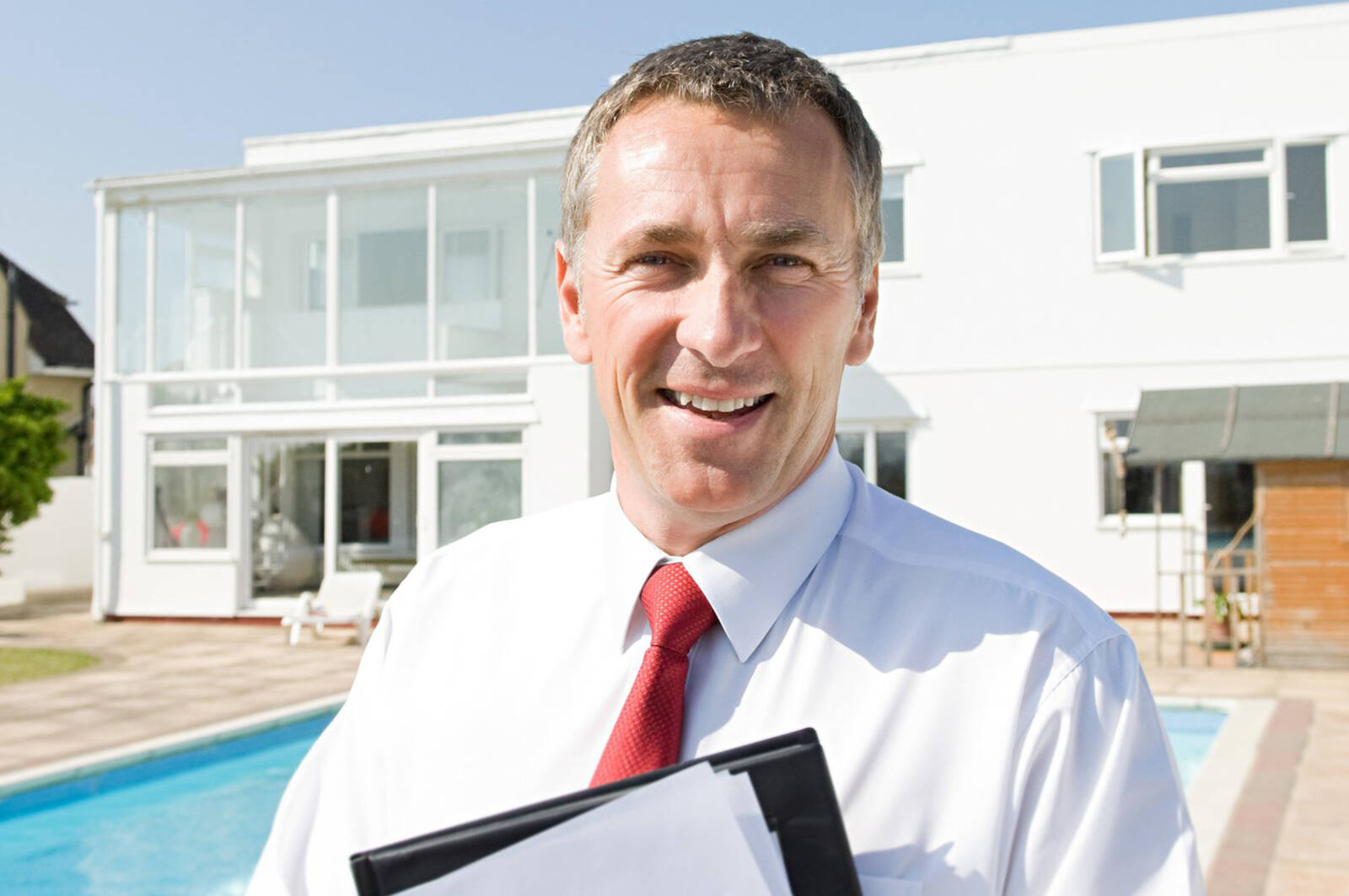 Makler vor Haus mit Pool